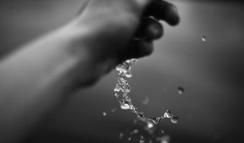 Hand pouring water in black and white