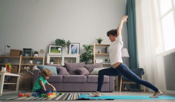 a woman and a child doing yoga in a living room